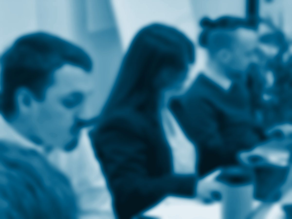 Tres personas trabajan con sus portátiles en una mesa compartida